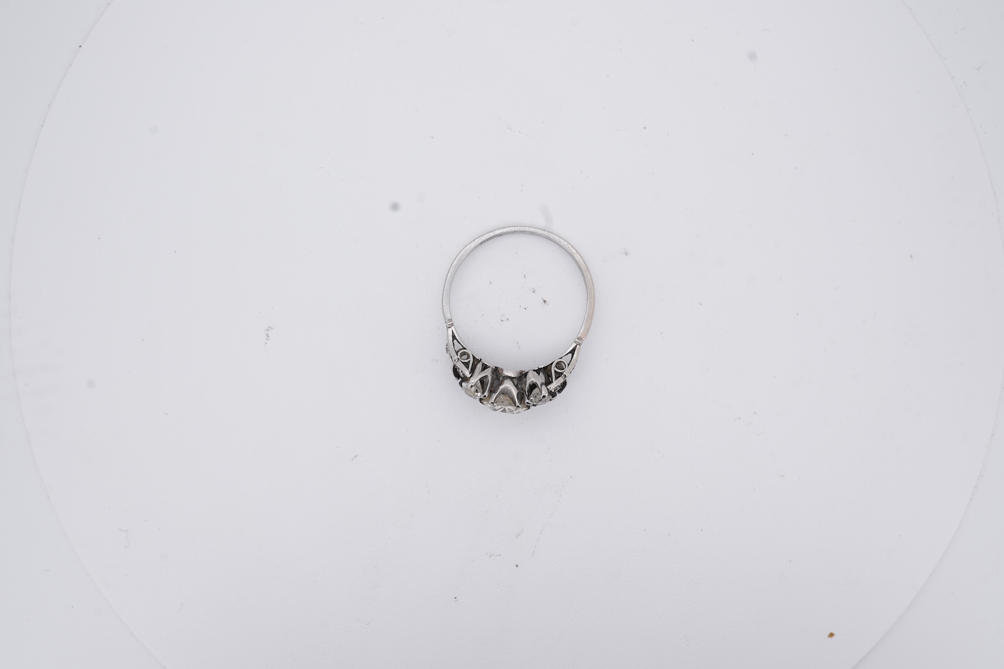 A white metal (stamped platin) and single stone diamond ring, flanked by four smaller diamonds and rose cut diamond chip set shoulders, size P, gross weight 3.8 grams.